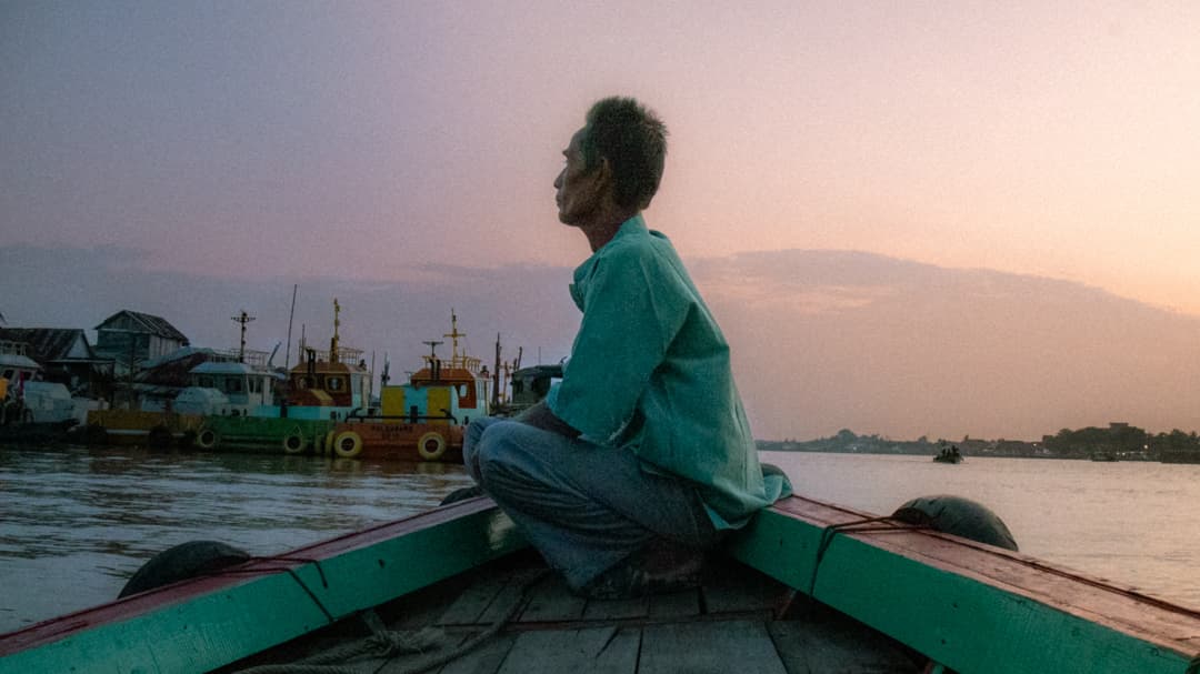 Hombre local en bote navegando por el río Musi en Sumatra, Indonesia