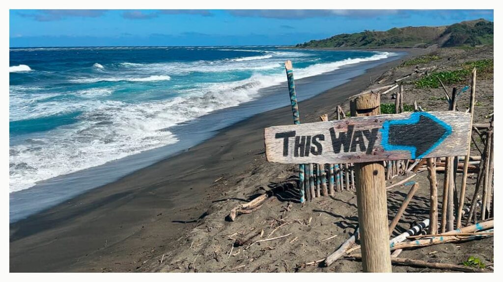 Mensaje-Fiji Cartel “This way” en la playa de Fiji, simbolizando el camino y las decisiones en el viaje.